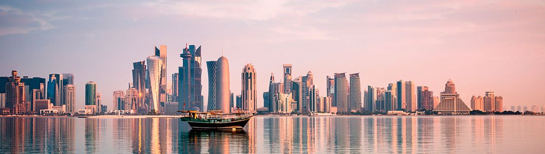 Dhow tradizionale davanti allo skyline di Doha al tramonto riflesso nell'acqua | MSC Crociere