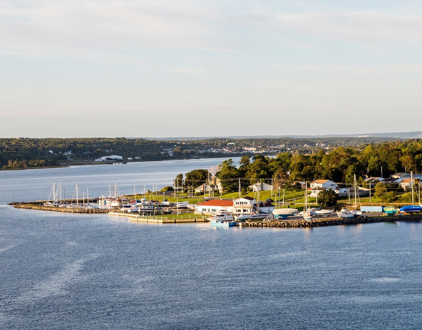 A scenic coastal town with a marina and sailboats, surrounded by lush greenery | MSC Cruises A scenic coastal town with a marina and sailboats, surrounded by lush greenery | MSC Cruises
