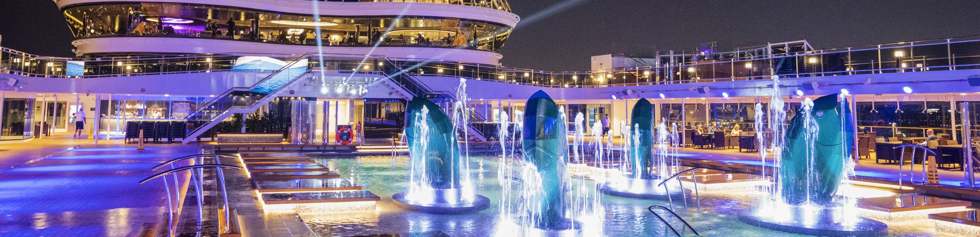 Illuminated pool deck with fountains and lounge areas on an MSC cruise ship at night | MSC Cruises Illuminated pool deck with fountains and lounge areas on an MSC cruise ship at night | MSC Cruises