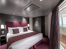 Luxurious cruise cabin with a king-size bed, modern decor, and a private balcony overlooking the ocean | MSC Cruises Luxurious cruise cabin with a king-size bed, modern decor, and a private balcony overlooking the ocean | MSC Cruises